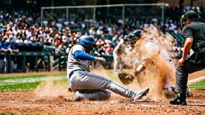 Baseball player sliding feet-first into base with dust cloud