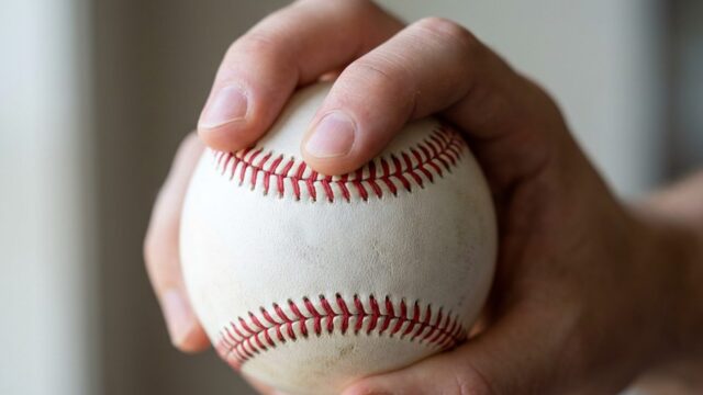 Two seam fastball grip showing fingers on narrow seams of baseball